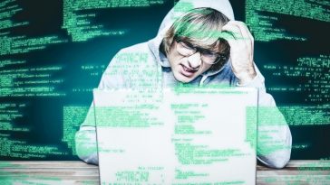 composite image of man in hood jacket hacking a laptop
