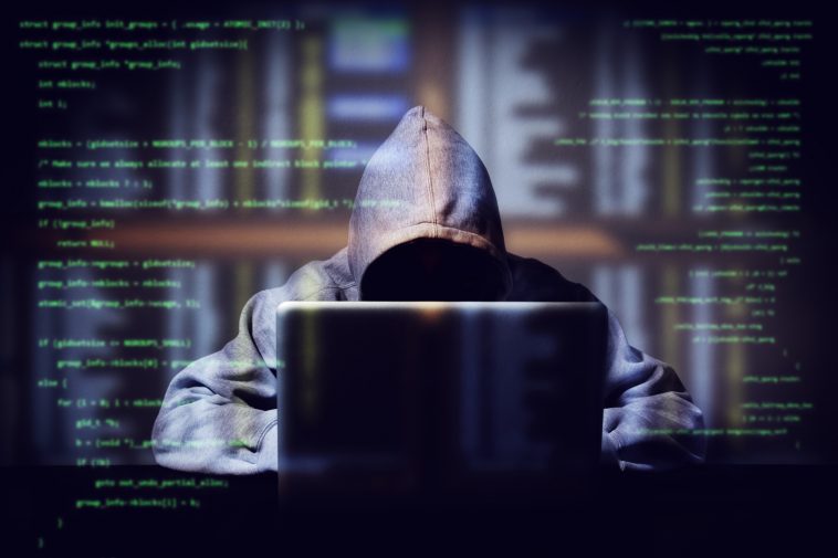 hacker working on a computer code with laptop double exposure with digital interface around at background internet crime hacking and malware concept anonymous face