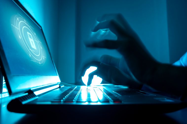 a computer programmer or hacker prints a code on a laptop keyboa